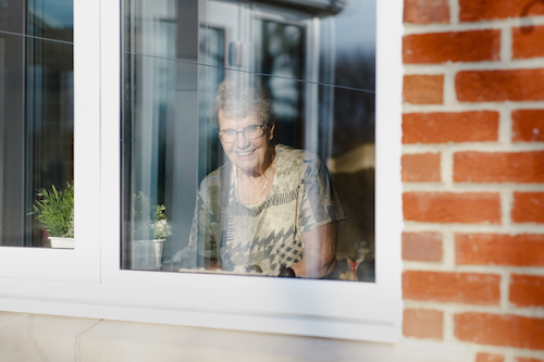 Vrouw kijkt door het raam naar buiten